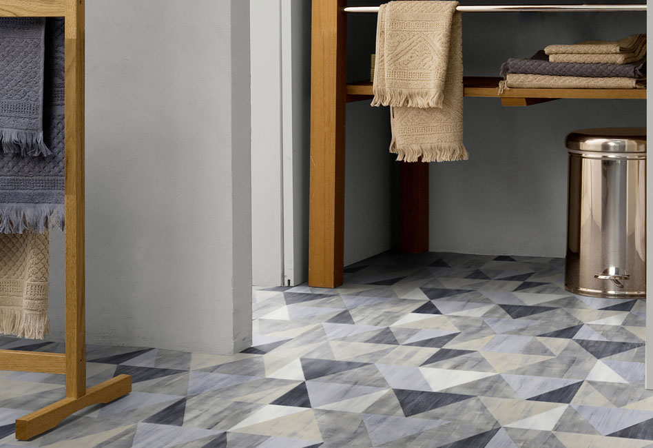 Dans une entrée, un joli sol vinyle qui décline des formes géométriques en losange de plusieur teintes alant du bleu-gris à l'anthracite..
