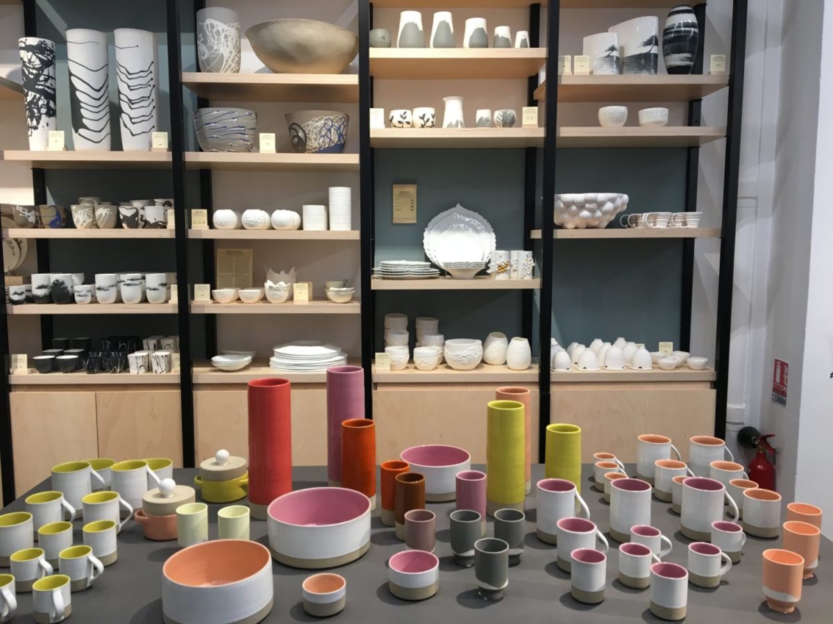 des rayonnages de vaisselle (bols assiettes, vases, petits mugs, en céramique bicolores, balnc à l'extérieur et courleurs vives à l'intéreiur. Phtoto prise à l'entrée du concept store Empreintes