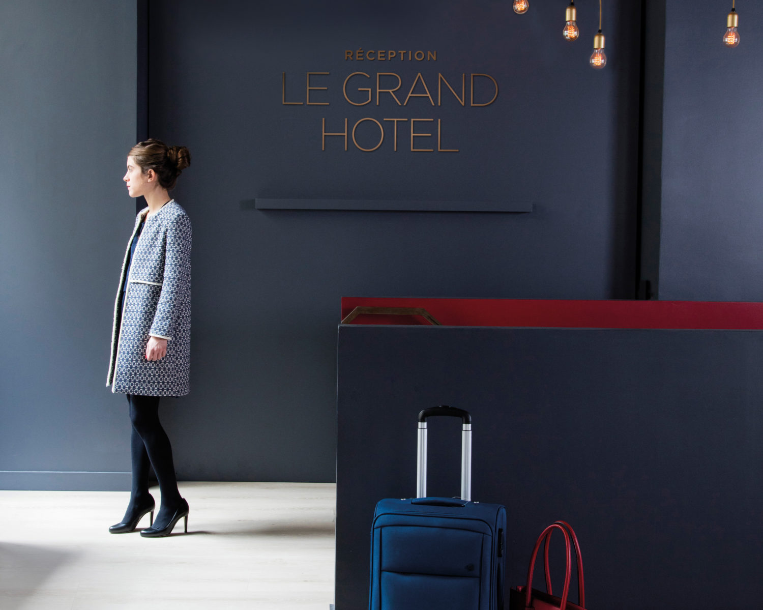 un hall d'hôtel chaleureux avec un parquet BerryAlloc au sol. Un ejeune femme élégante regarde vers l'extérieur