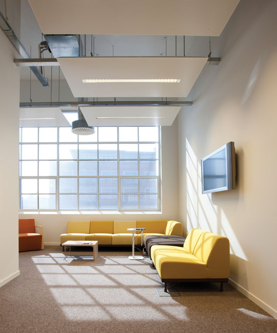 Style industriel : Un salon d'esprit industriel installé dans un loft. Canapés jaunes et lumière à foisons.