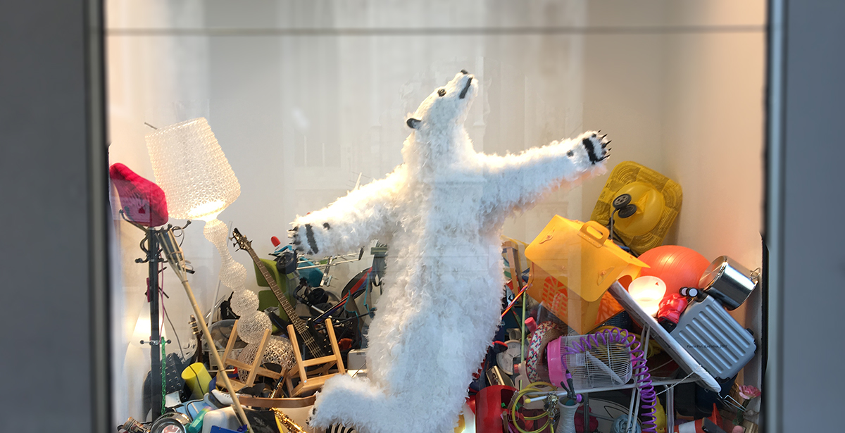 un grand ours blanc en peluche danse dans une vitrine pleine de bazar !