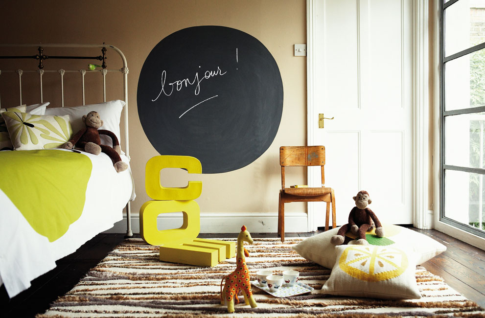 dans une chambre d'adolescent, 3 grandes lettres métalliques bombées en jaune fluo font la déco. Au mur une peinture tableau noir Julien sur laquelle est écrit "bonjour !"