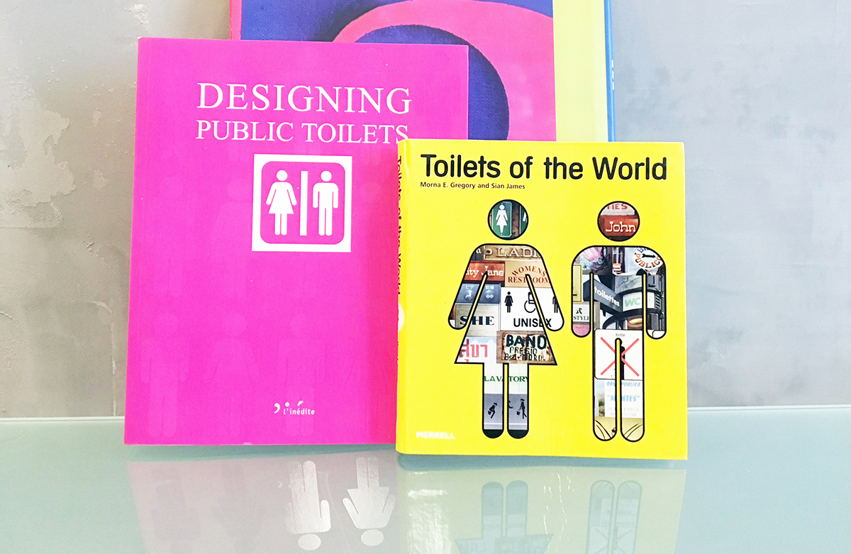 Deux livres sont posés devant un mur gris patiné : Toilets of the world et Designing Public Toilets