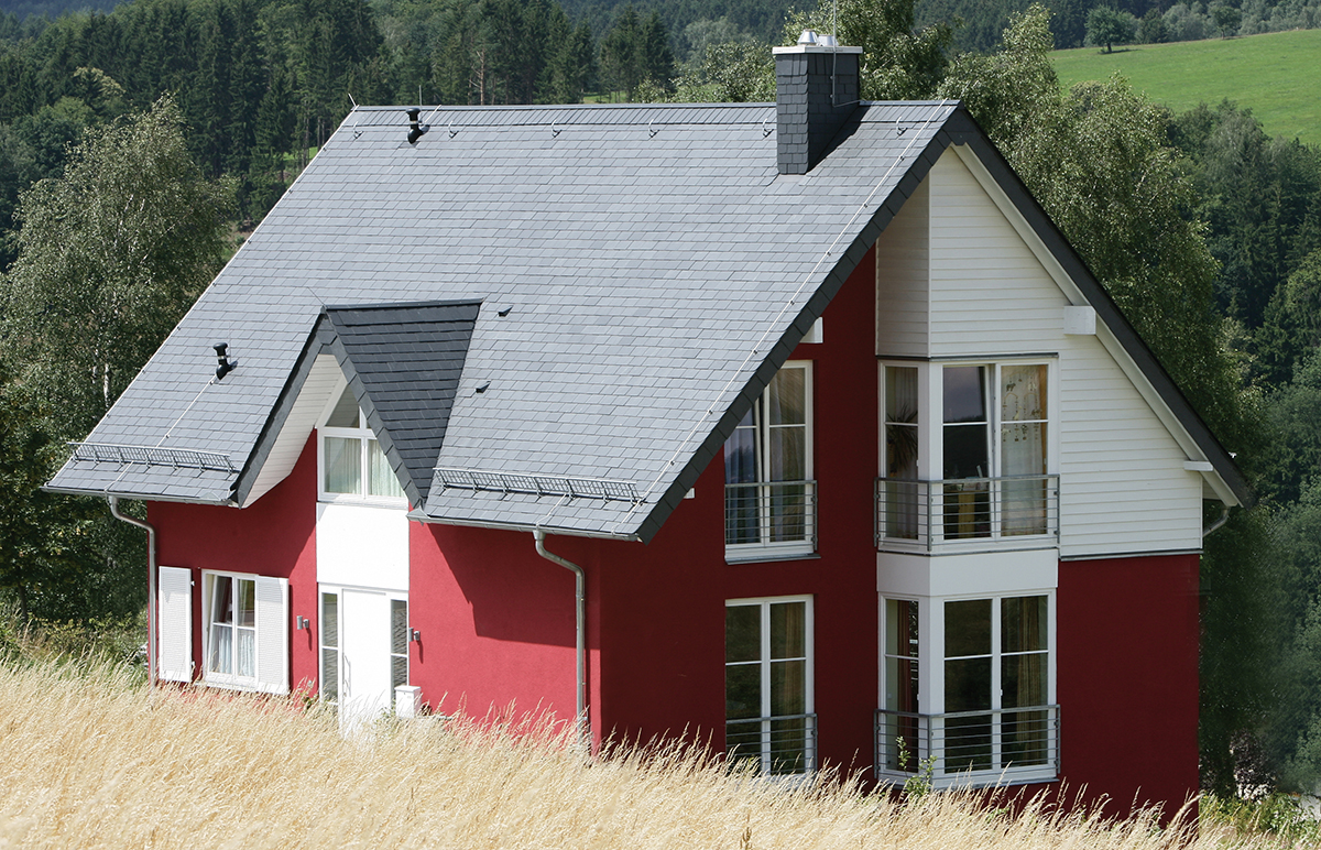 Une belle maison en pleine campagne. Sa façade rouge vif et son toit en ardoise naturelle lui donnent dynamisme et originalité