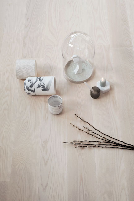 un parquet doux de teinte beige est phtographié en gros plan avec quelques petits vases posés par terre