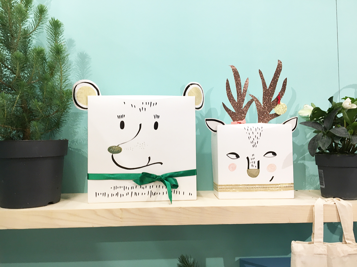 Deux décoration de Noël faites à la main avec des boîtes en carton. L'une représente une tête d'ours et l'autre une tête de renne. sur un fond de mur peint en couleurs vert d'eau