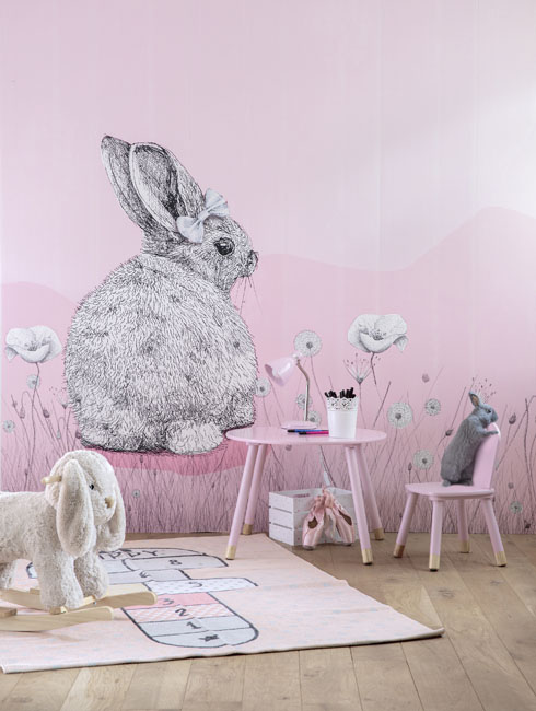 une chambre de petite fille avec au mur, sur fond rose, un grand lapin dessiné comme au stylo à bille