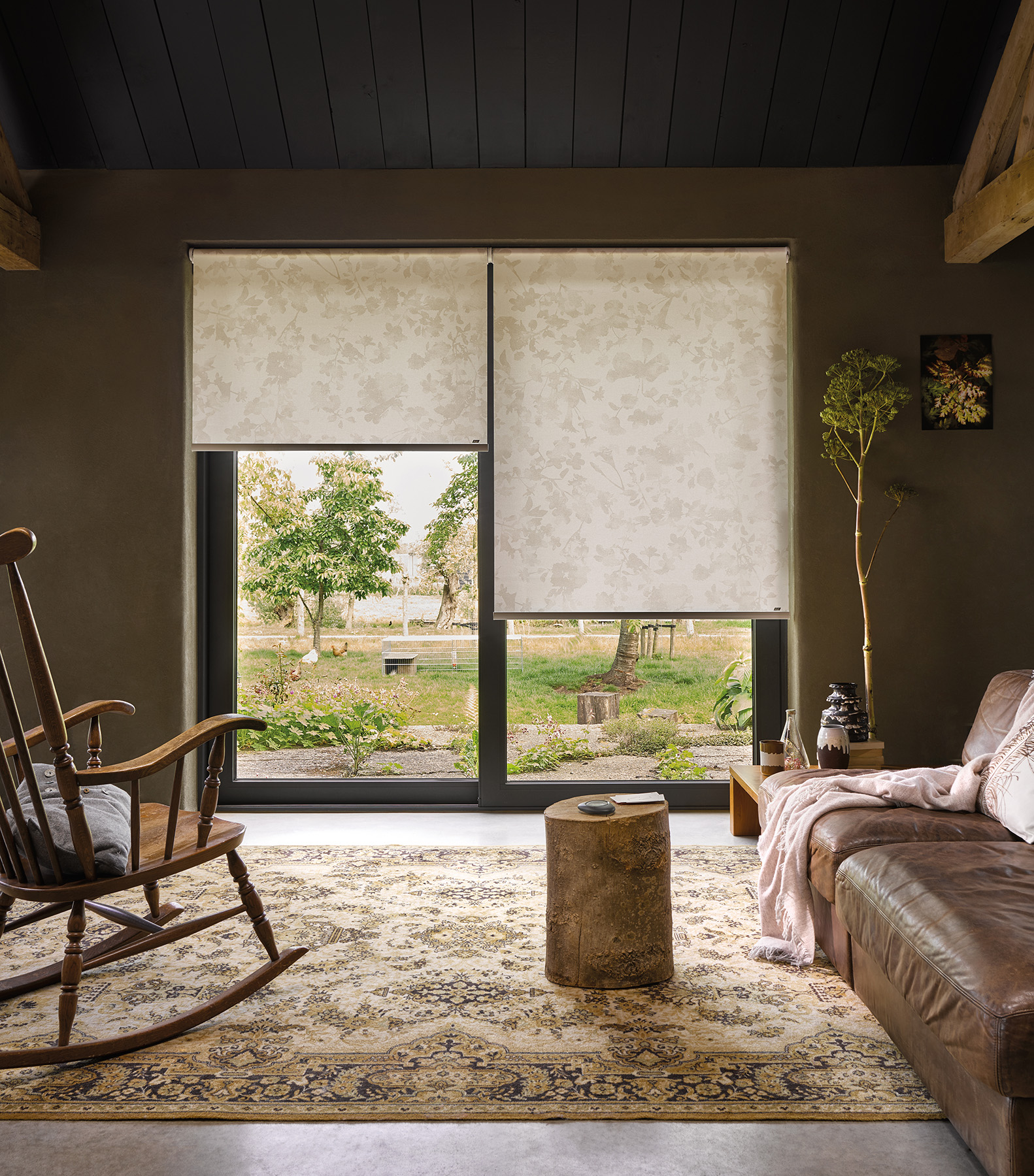 un salon très cosy est équipée de baie vitrée à deux vantaux avec des tsores rouleaux Luxaflex beige à motif végétal pour un air de printemps