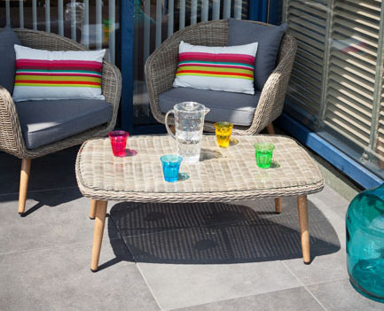 Une terrasse dont l'étanchéité en dalles de grès cérame Siplast, avec unsalon de jardin en rotin. Sur la table une carafe d'eau et de sverres en couleurs.