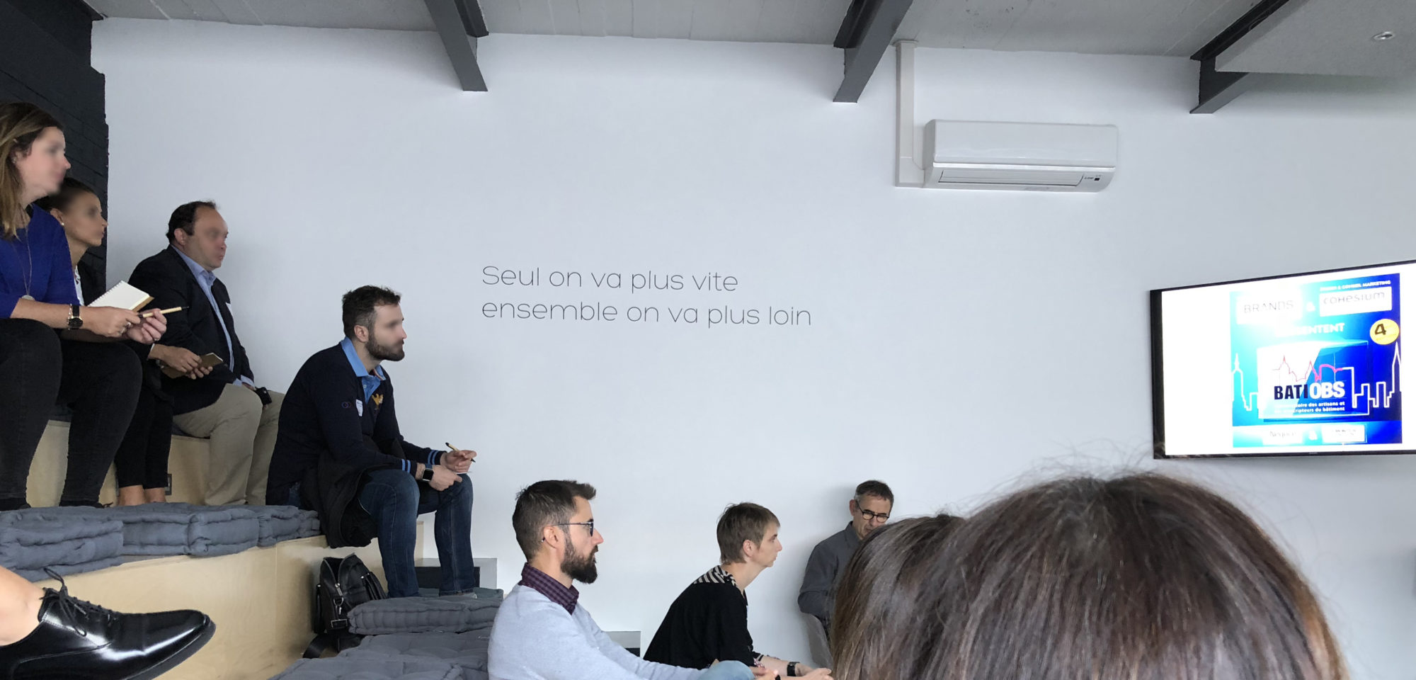 quelques personnes assisses sur de stribunes regardent la présentatyion powerpoint du baromètre BATIOBS. Les artisans et le digital