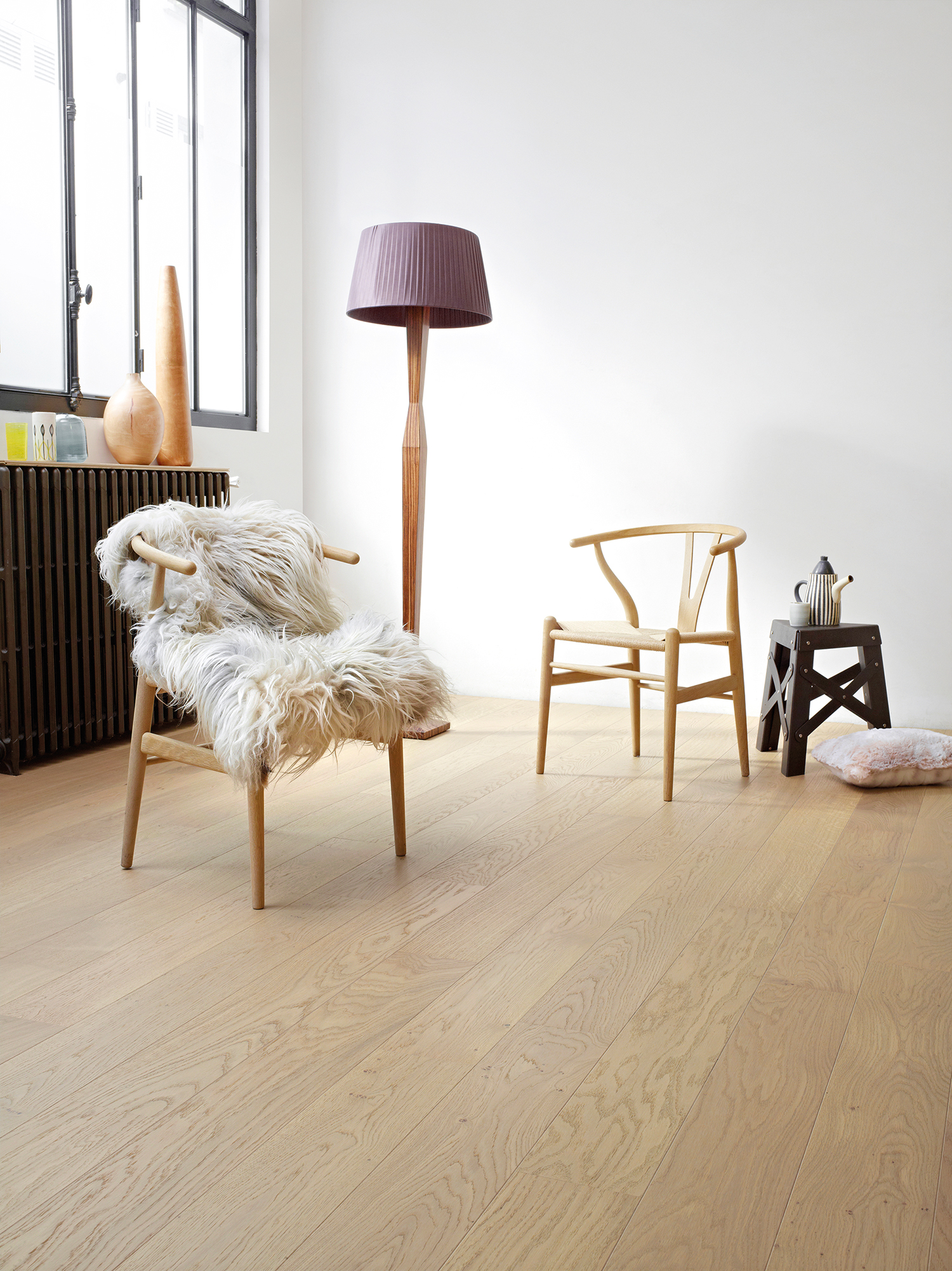 Un plaid en poils de chèvre posé négligemment sur une chaise en bois naturel au style très épuré. Parquet BerryAlloc