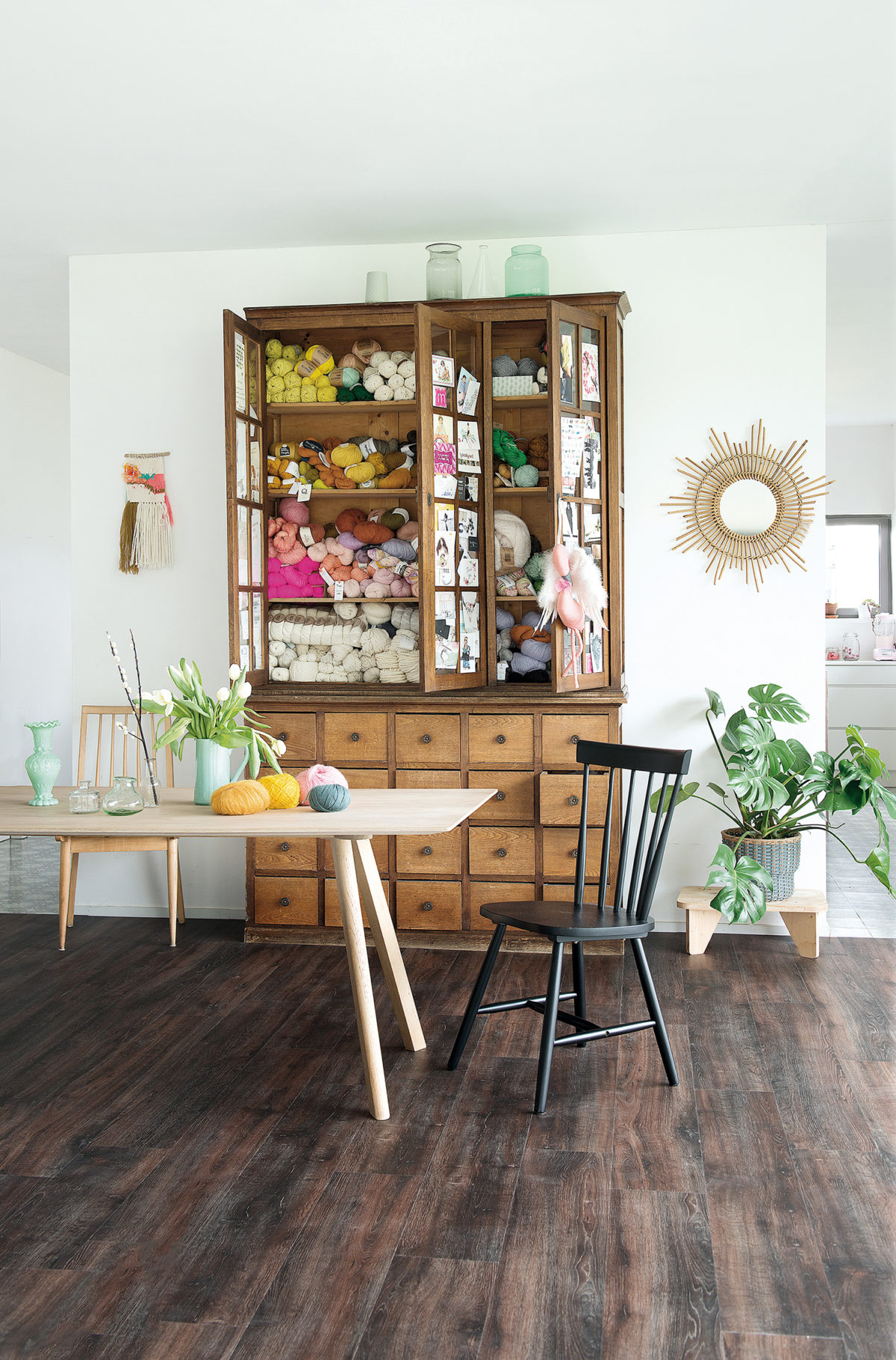 Armoire en bois recyclé qui renferme des pelotes de laine, parquet naturel rustique BerryAlloc, plantes et bouquets, miroir en rotin… une atmosphère Scandicraft.