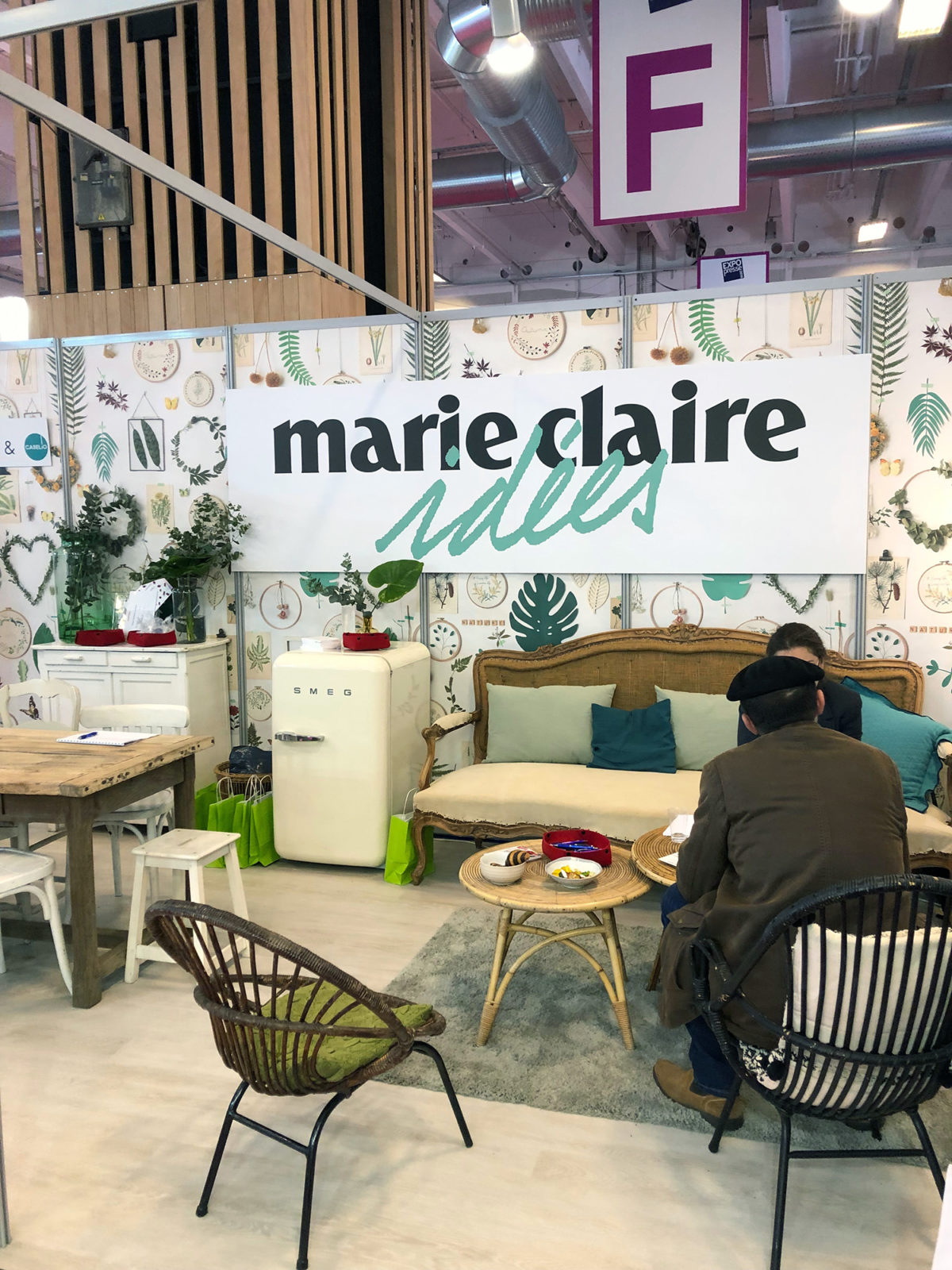 jolie mise en scène sur le satnd Marie-Claire idées, EXPOPRESSE 2019 - ambiance chaleureuse avec un petit salon en rotin, un papier jungle et un sol BerryAlloc.