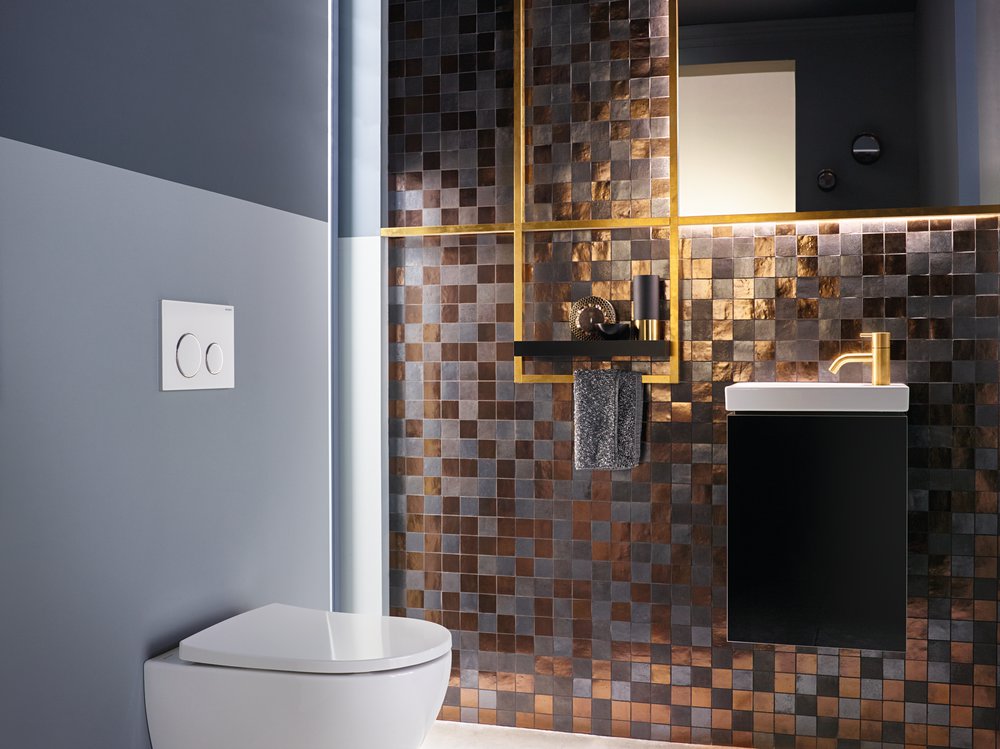 un coin toilette très sophostiqué avec une mosaïque au mur, des wc suspendus et des accessoires dorés : plaque de déclenchement, robinet, cadre de miroir...