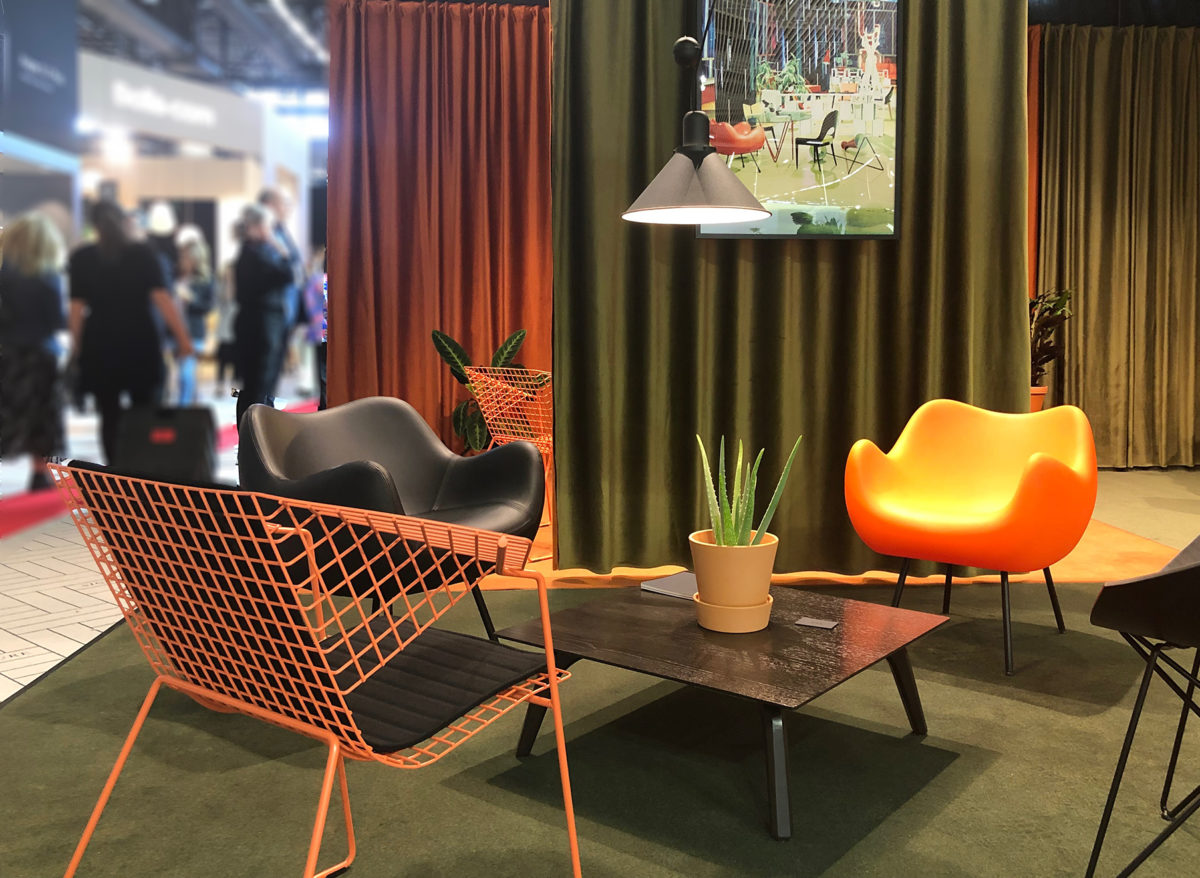 sur le stand VZOR une mise en scène de fauteuils orange avec de srideaux verts et orange à l'arrière plan