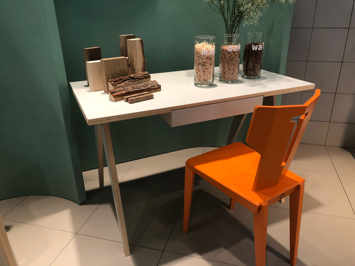 une chaise orange vif devant un bureau en bois blanc et un mur peint en vert