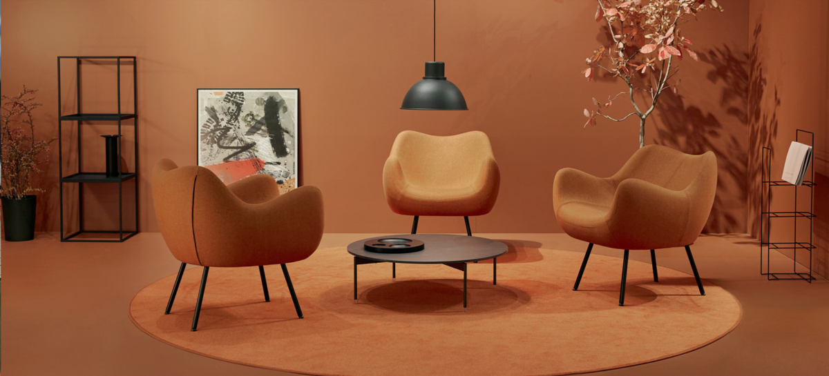 un salon très fifities chez Vzor : fauteuils oarnge table basse vintage, suspension métallique, murs orange