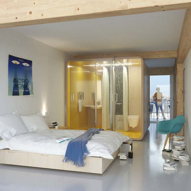 un module bois, comme un cube compact, est nstallé derrière un lit dans une chambre. Il comporte une salle d'eau complète