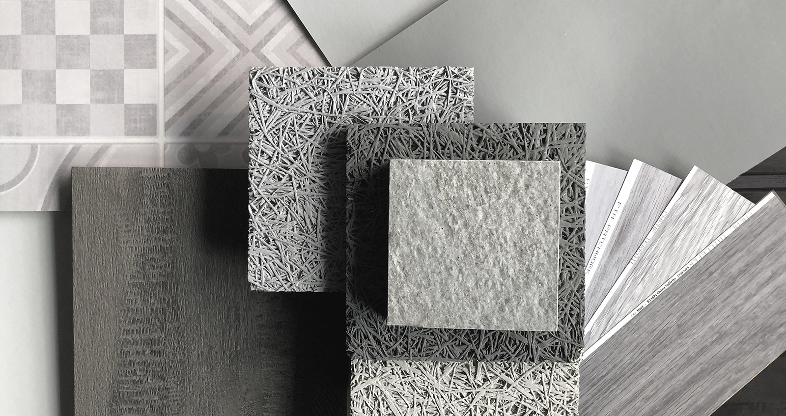 un pêle même de matériaux dans les tons gris constituent un joli Moodboard tendance : échantillons de parquets, de plafond acoustique, de revêtement mural...