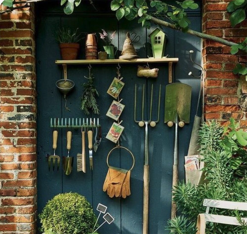 de soutils de jardin rangés contre une porte peinte en vert